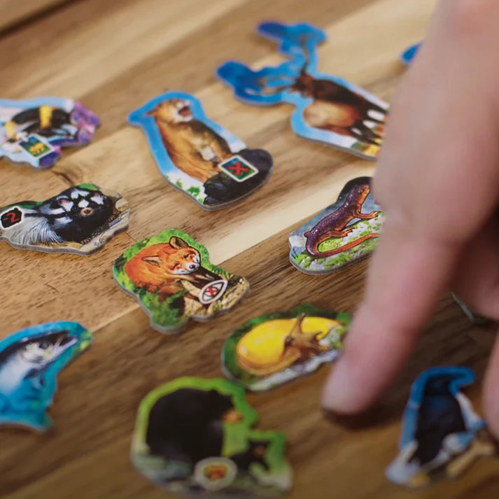 Canopy board game with Hand interacting with animal-themed game pieces on a wooden surface