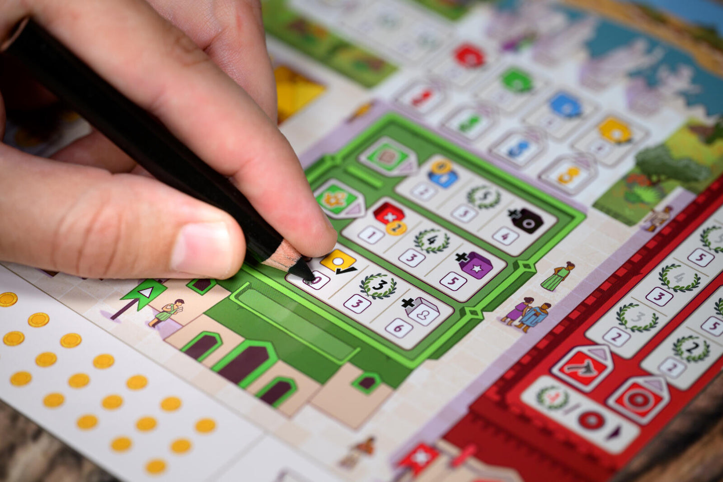 Hand holding a pen over a colorful game board with various symbols
