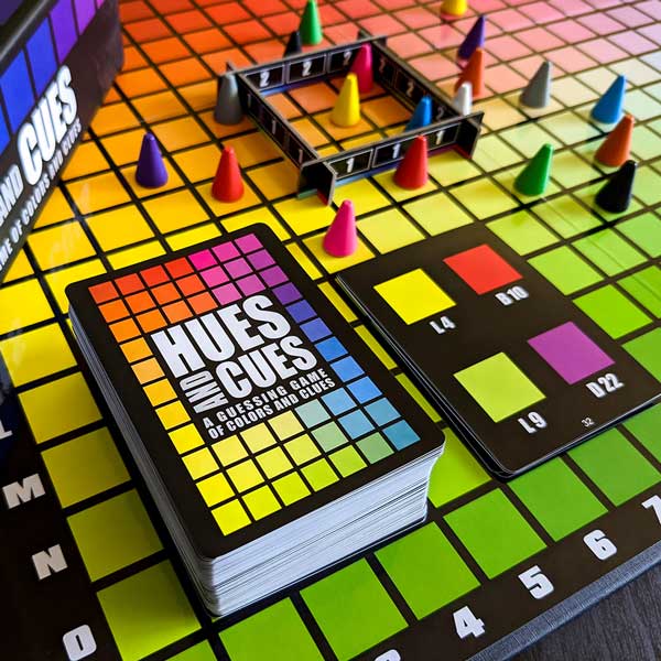 Colorful board game 'Hues and Cues' with cards and game pieces on a grid.
