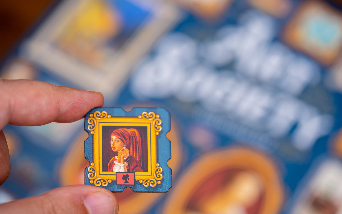 Small tile from Art Society with a portrait held in front of a larger card with text and images.