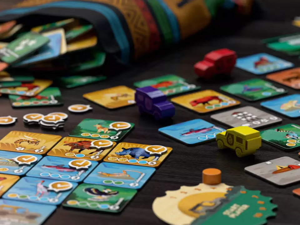 Board game with colorful cards and toy cars on a dark surface