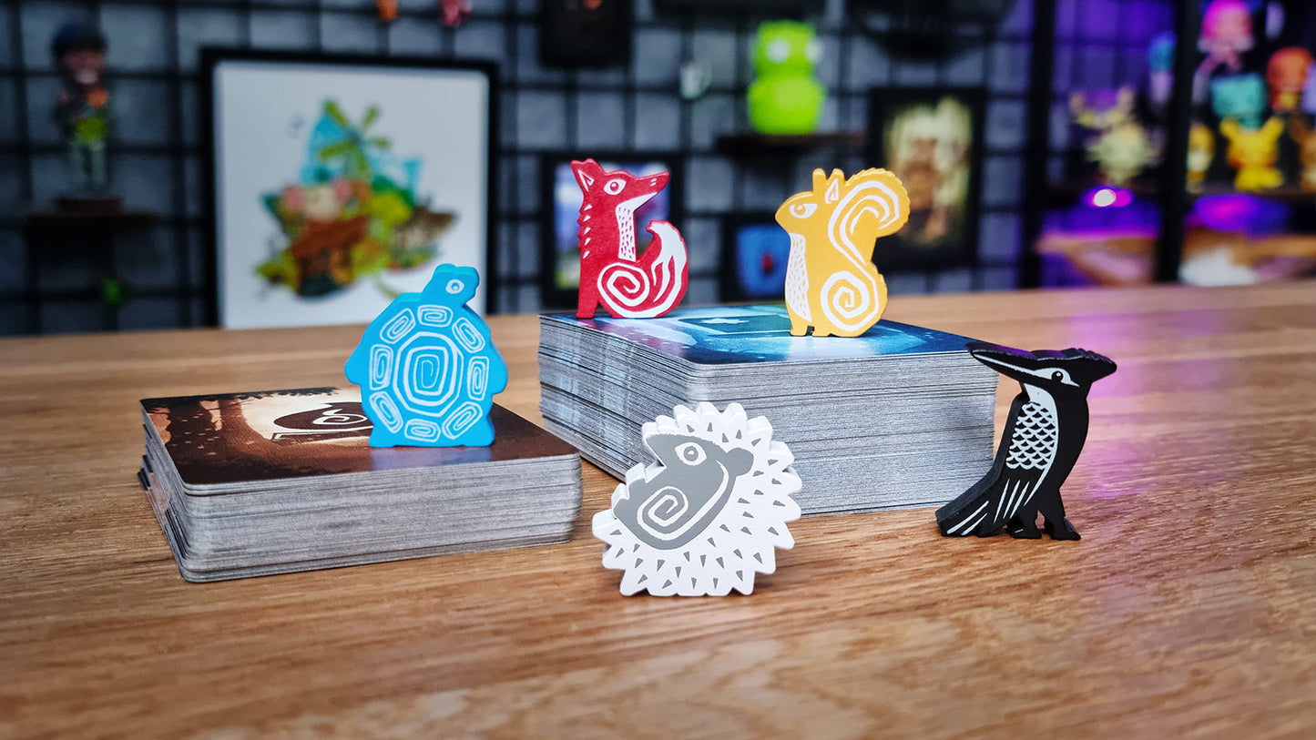 Collection of colorful figurines and cards on a wooden surface with a blurred background Ember Leaf