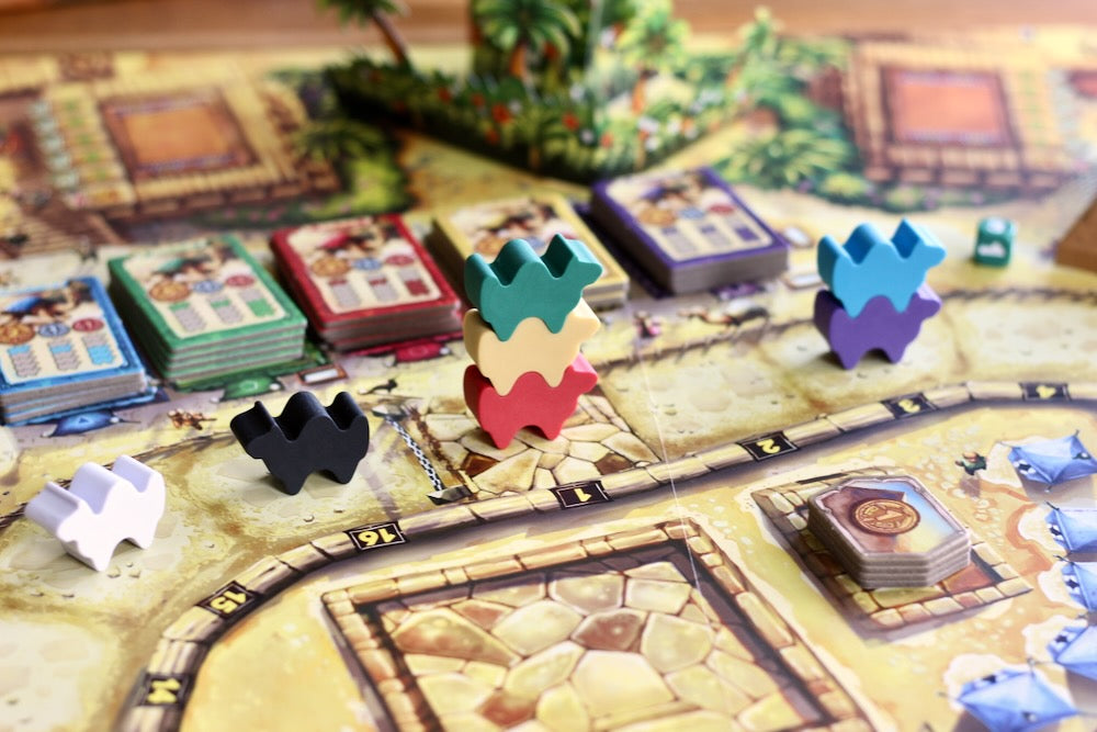 Board game with colorful game pieces and cards on a wooden board for Camel UP