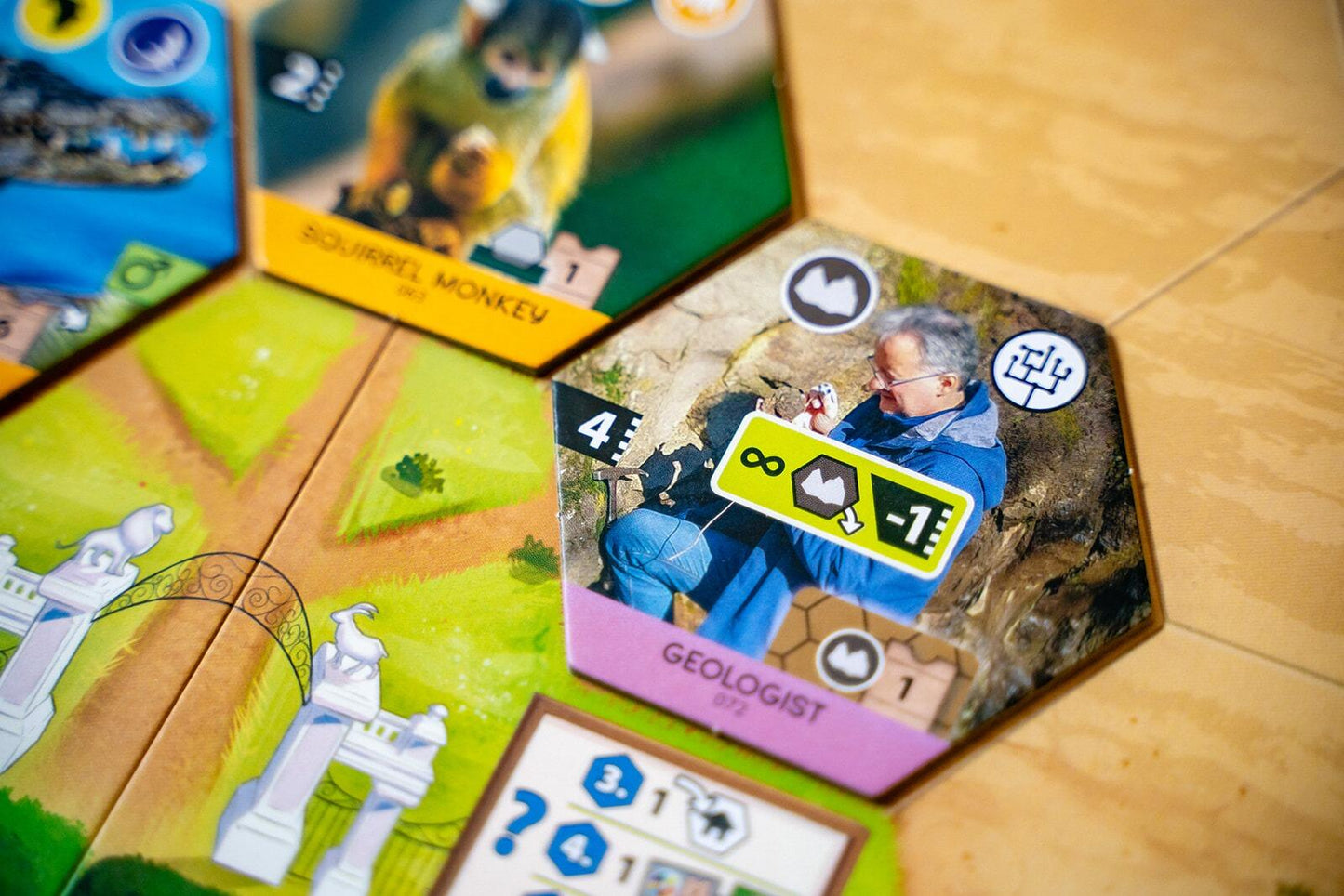 Sanctuary Close-up of a board game with cards featuring characters and icons on a wooden surface.