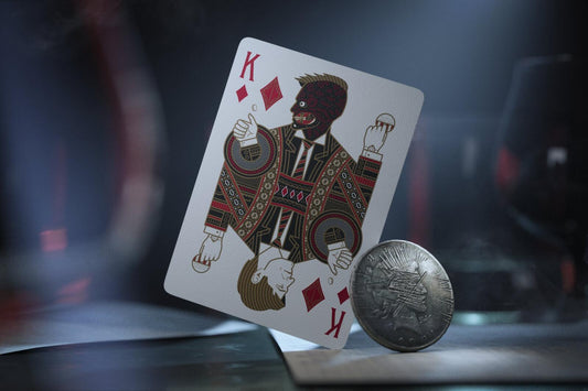 Batman playing cards ofa king design and a coin on a dark background