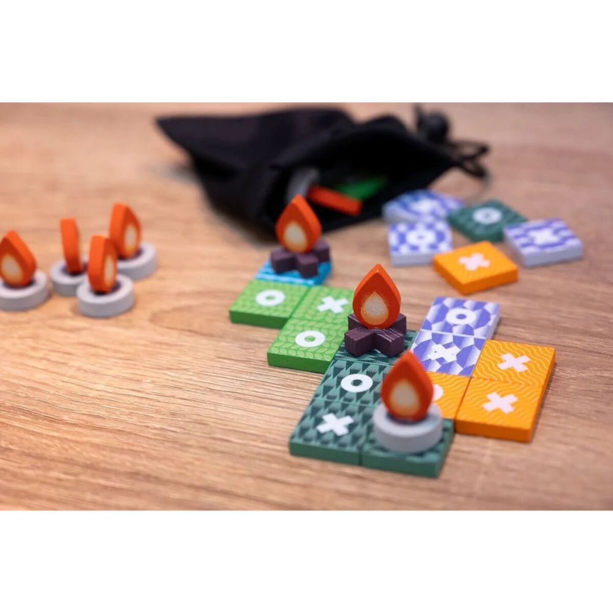 Colorful game pieces with campfire designs on a wooden surface