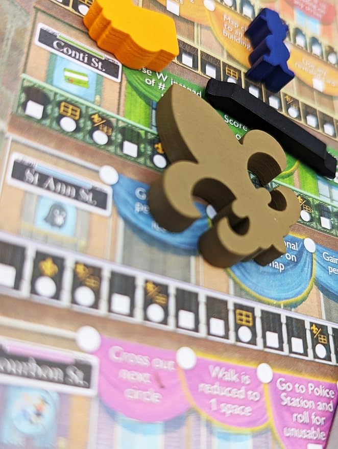 Close-up of a board game featuring 3D player tokens in gold, blue, black, and orange on a colorful city-themed game board with street names and turn tracks.