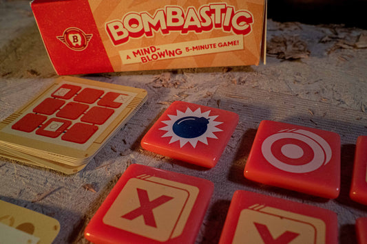 Bombastic Board game with cards and tokens on a textured surface, featuring the 'Bombastic' brand.