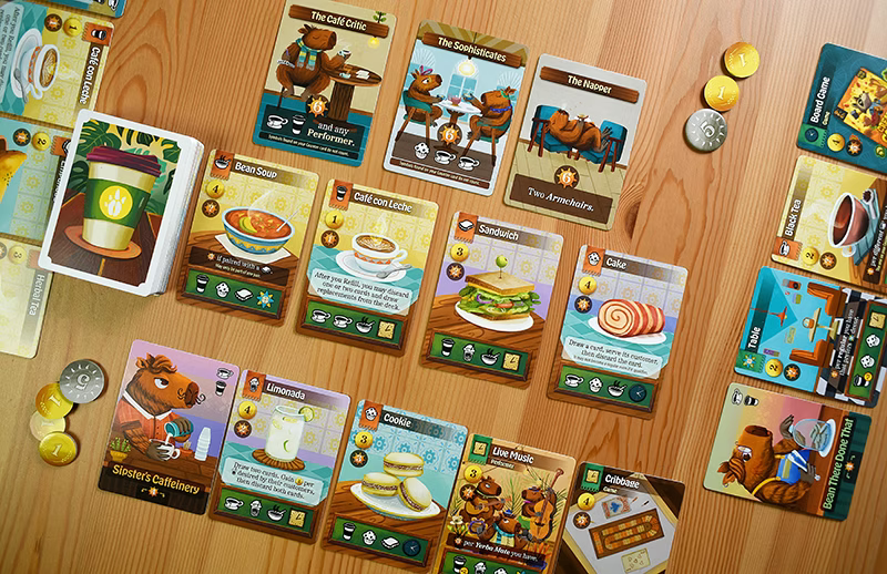 Cafe Baras Collection of board game cards and coins on a wooden surface