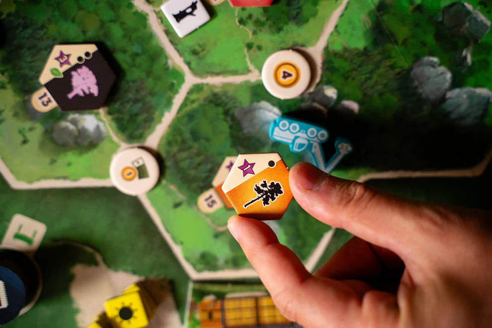 Hand holding a game piece over a Forestry board game with various markers and cards.