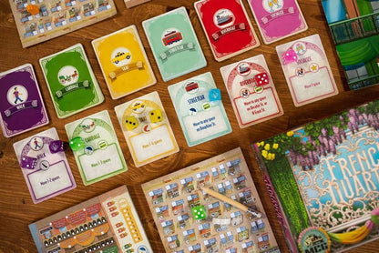 Collection of colorful game cards on a wooden surface with a game box partially visible.