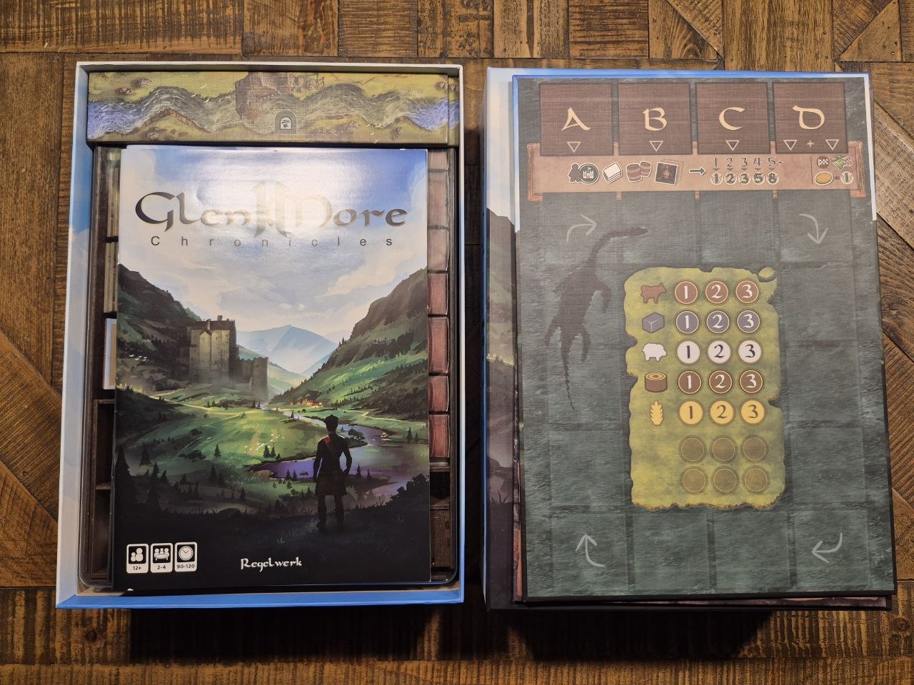 Glenmore Chronicles board game set shown with its illustrated box on the left and the game board on the right, placed on a wooden surface.