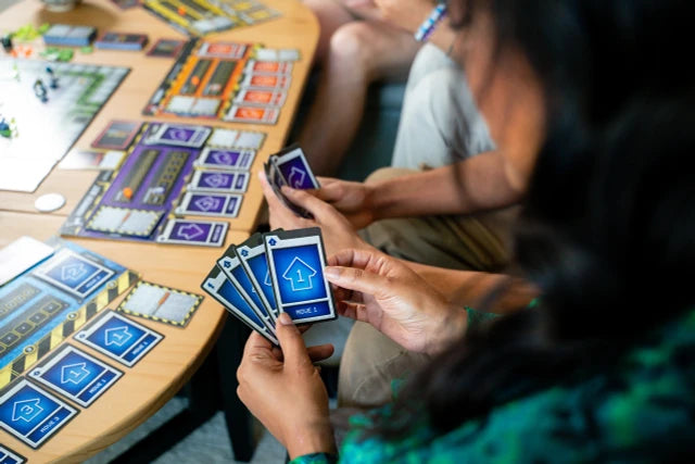 Two people playing a board game Robo Rally with cards on a table