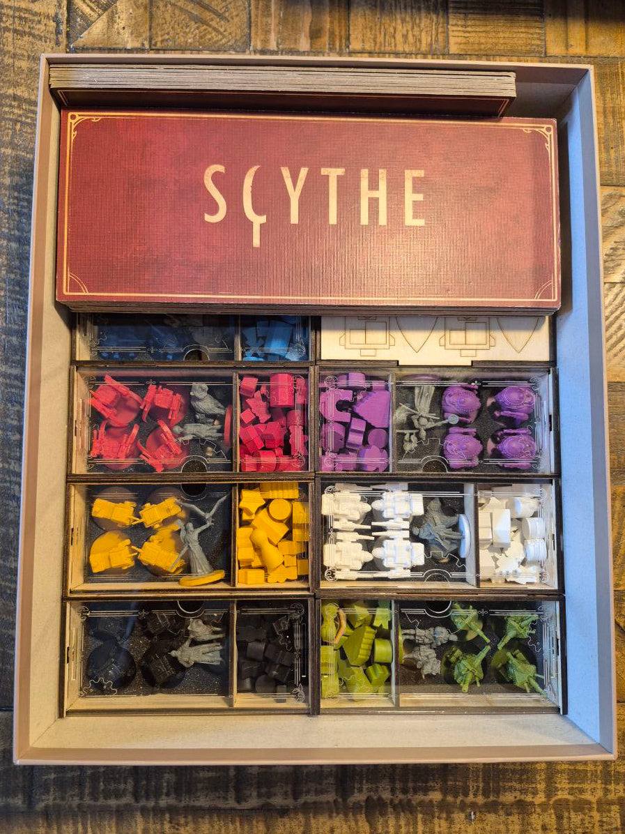 Board game box with 'Scythe' branding and compartments filled with miniature figures on a wooden surface.