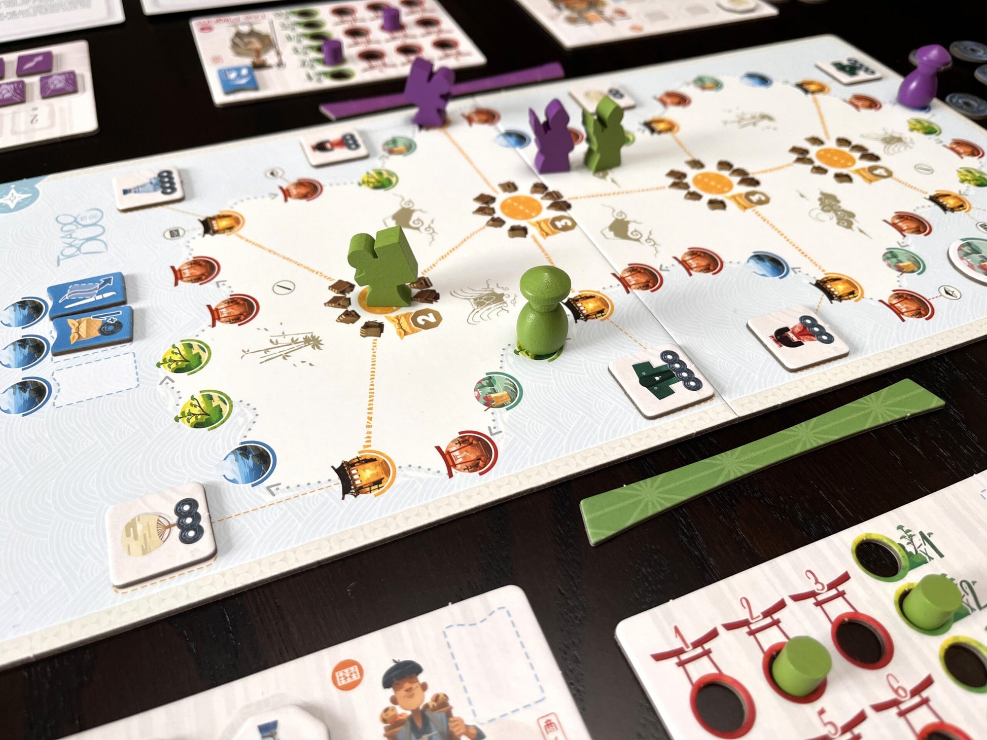 Tokaido Duo Board game in progress with colorful game pieces and cards on a dark surface