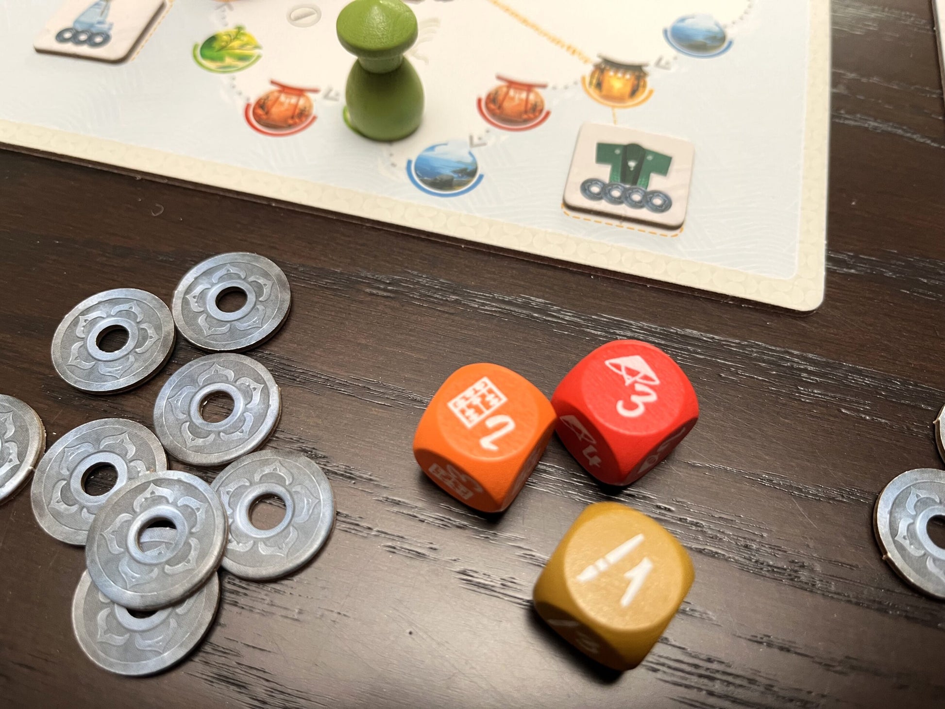 Tokaido Duo Board game pieces including dice and tokens on a wooden surface
