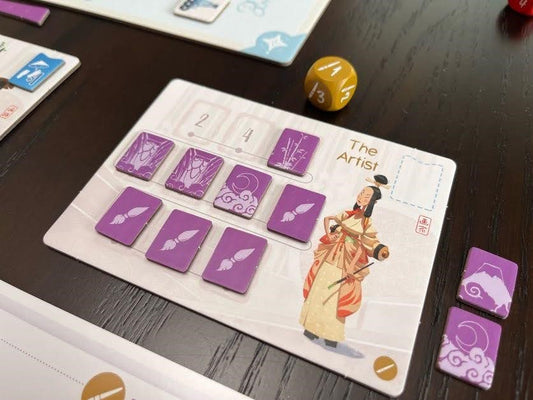 Tokaido Duo Board game component with cards and a die on a dark surface