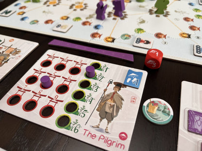 Tokaido Duo Board game with character card labeled 'The Pilgrim' on a wooden table