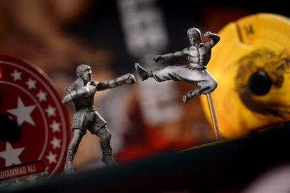 Two action figure toys in a dynamic pose with a blurred background featuring a sports ball and logo.