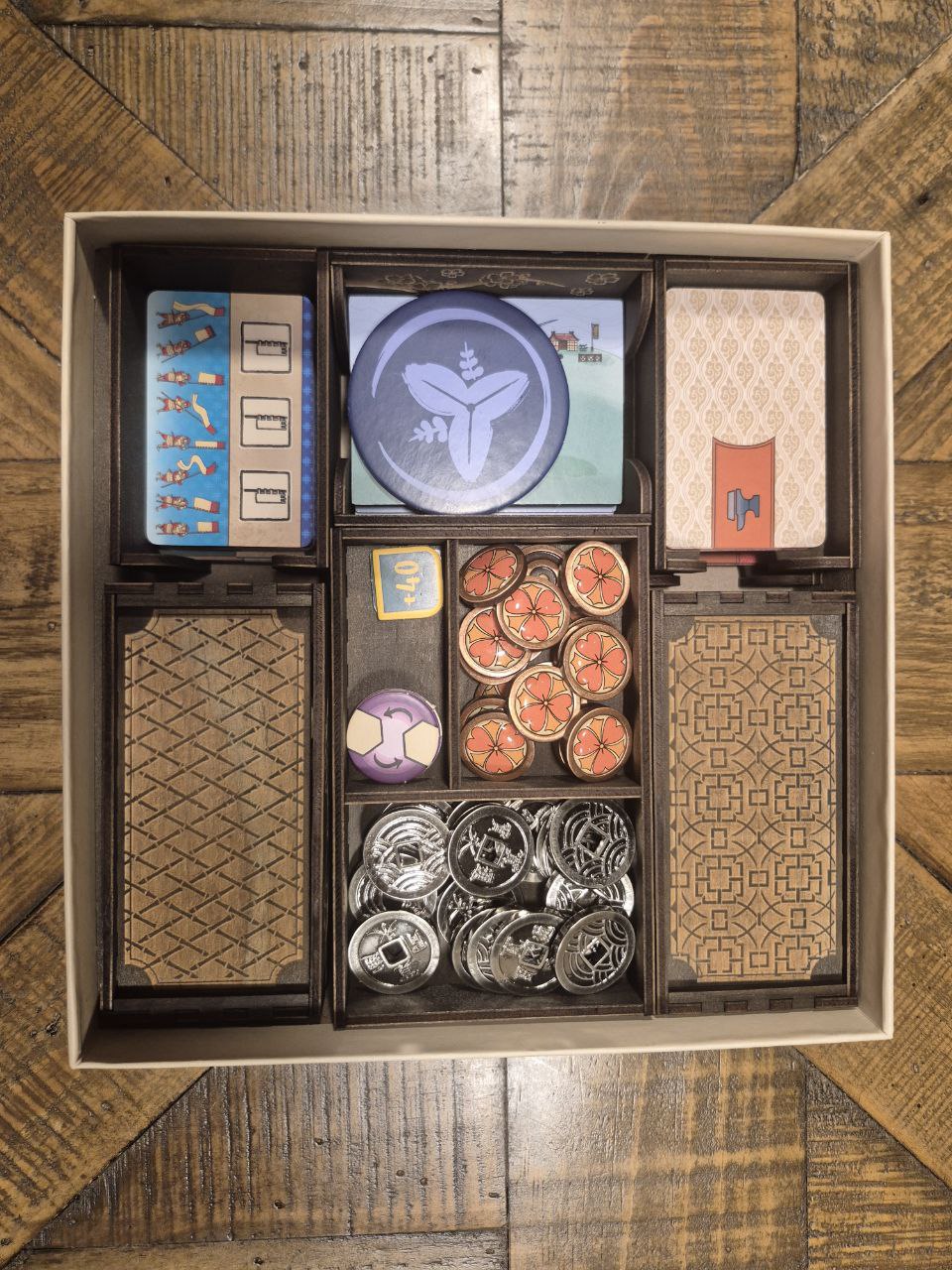 3DLevelup Board game timber organiser with collection of board game components including cards, tokens, and  a box on a wooden surface.