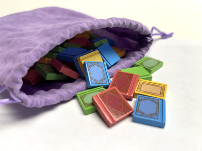 A place for all my books Colorful card game pieces spilling out of a purple drawstring bag on a white background