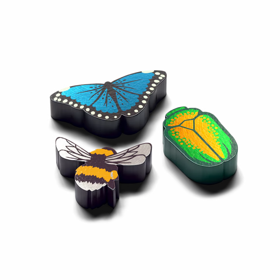 Three small insect-shaped accessories on a black background: a blue butterfly, a bumblebee, and a green beetle with yellow and orange wing patterns.