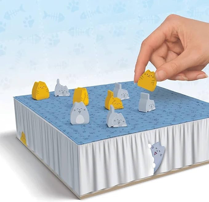 Hand playing with a miniature cat set for Boop the board game set on a blue background