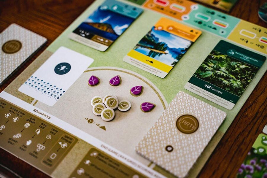 Earth Board game components including cards and tokens on a wooden surface