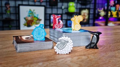 Collection of colorful figurines and cards on a wooden surface with a blurred background Ember Leaf