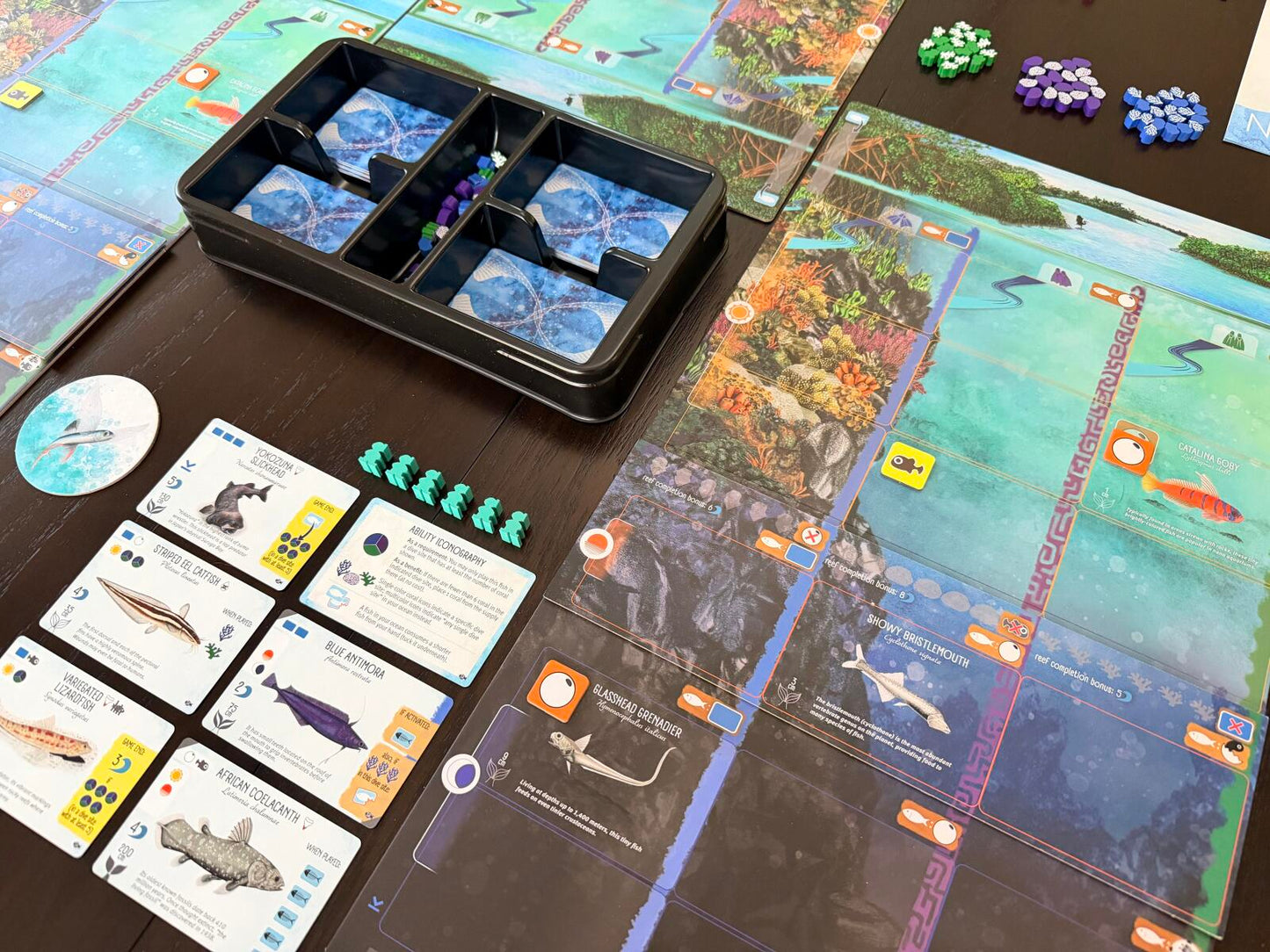 Board game setup with cards, pieces, and a map on a table
