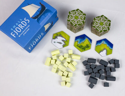 Board game components including hexagonal tiles and cubic tokens with 'Small Fjords' packaging.