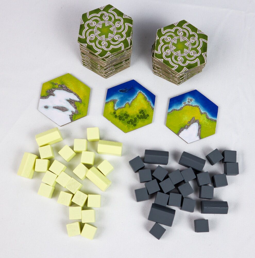 Hexagonal game pieces with various designs, small yellow cubes, and black rectangular tiles on a white background.