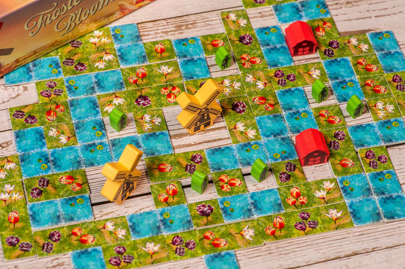Board game with colorful tiles and small buildings on a wooden surface
