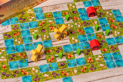 Board game with colorful tiles and small buildings on a wooden surface
