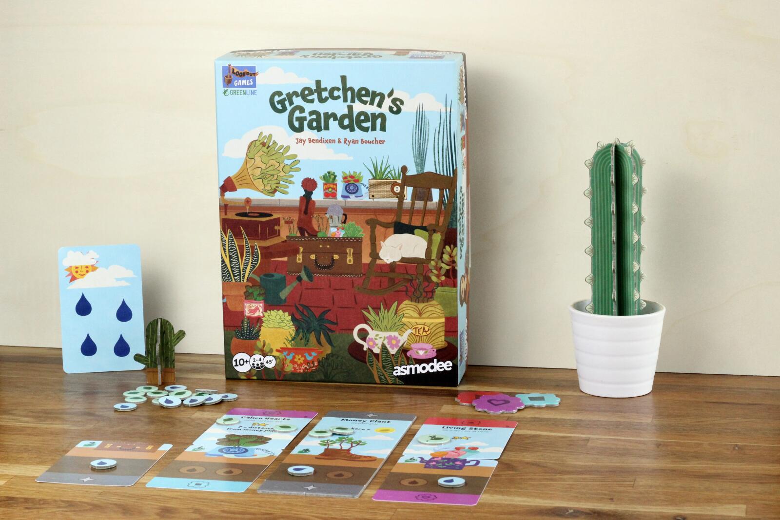 Board game box titled 'Gretchen's Garden' on a wooden surface with cards and a cactus.