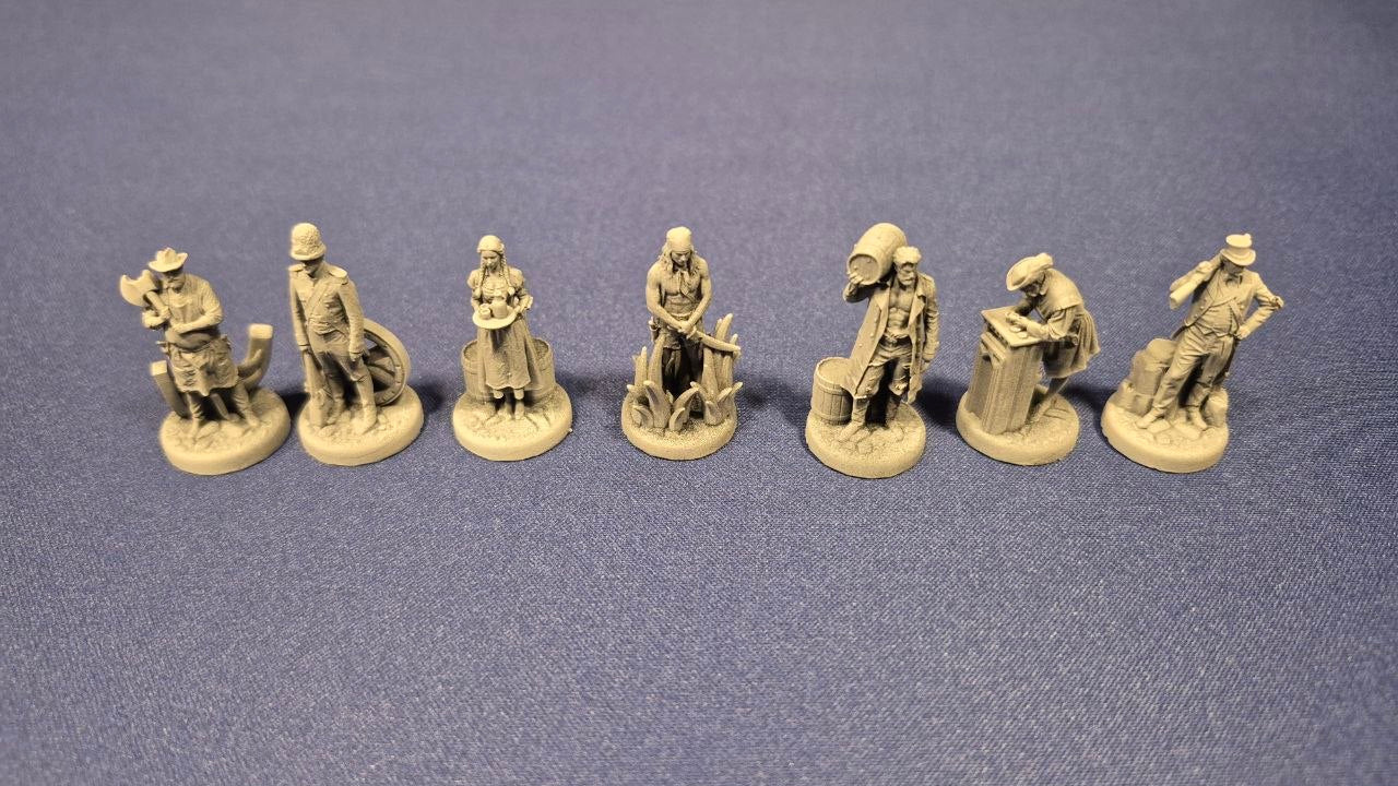 A set of seven unpainted gray plastic tabletop gaming miniature figures arranged in a row on a textured blue surface.