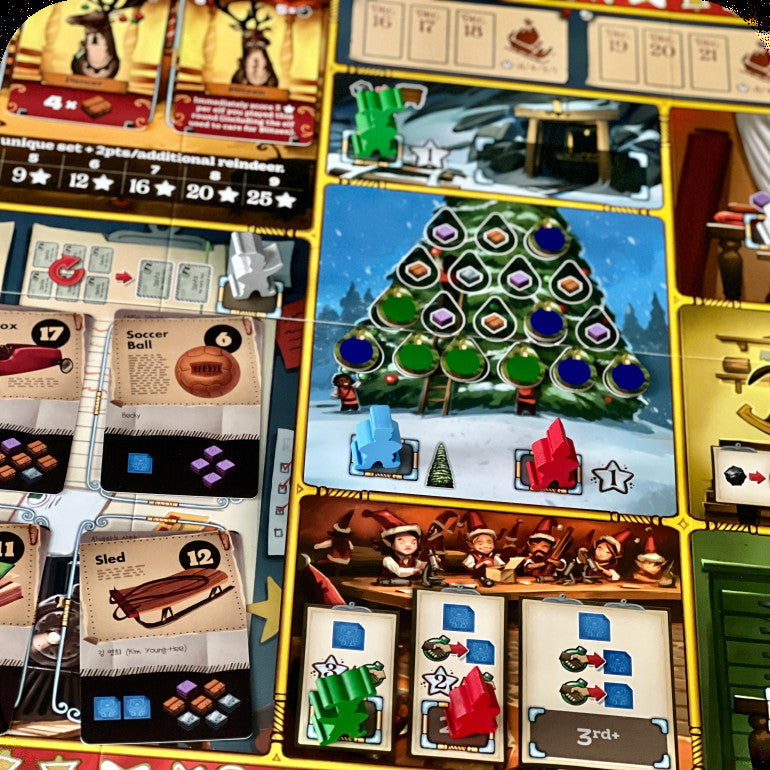 A close-up of a board game board featuring a Christmas tree building phase, player cards, resource tiles, and holiday-themed play areas with colorful game pieces.