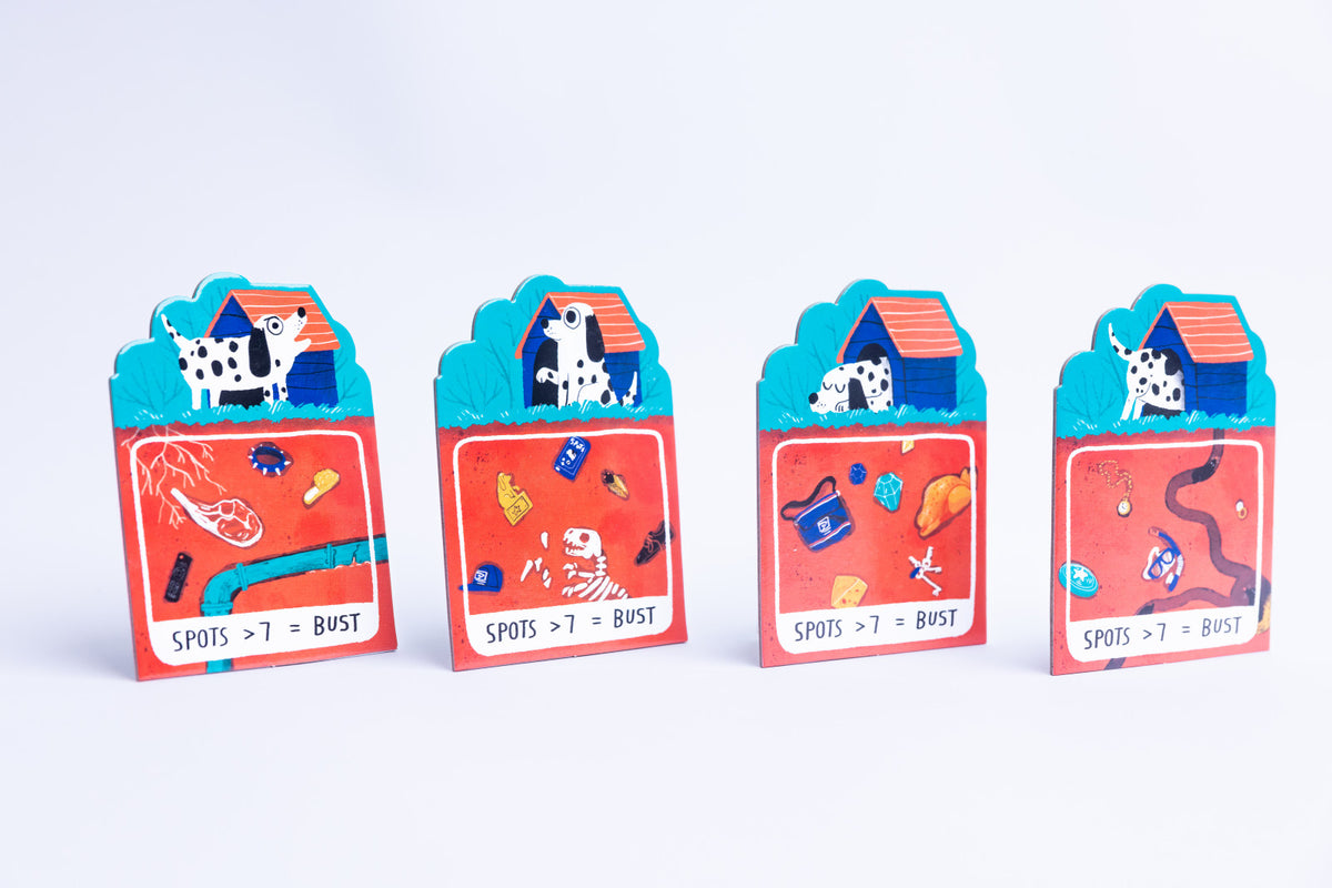 Four colorful dog house card games arranged in a row on a clean white background. Each card features a red lower section with treasure and clue illustrations, a blue middle section with a dog house, and a white top section with a dalmatian dog.
