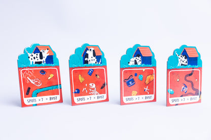 Four colorful dog house card games arranged in a row on a clean white background. Each card features a red lower section with treasure and clue illustrations, a blue middle section with a dog house, and a white top section with a dalmatian dog.