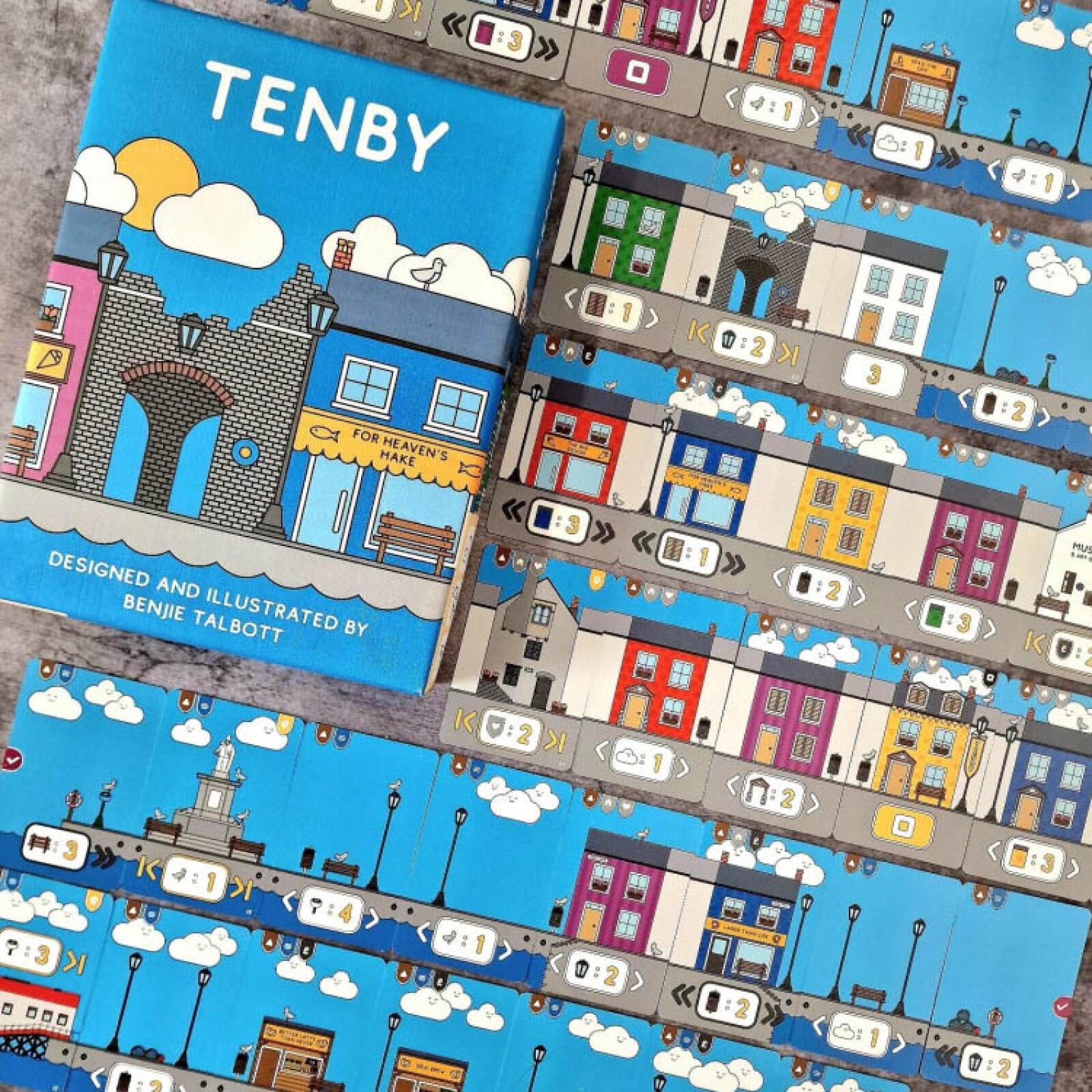 Board game titled 'Tenby' with colorful illustrations of a town on a blue background.