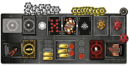 A top-down view of a card game board setup with multiple cards, chips, and game pieces arranged on a dark rectangular board. Visible elements include black and red playing cards, gold and red tokens, and stacks of circular chips in black, white, and gold.