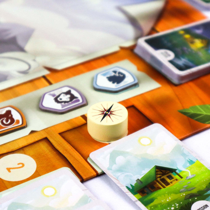The Peak Team Board game components including cards and character tokens on a colorful board