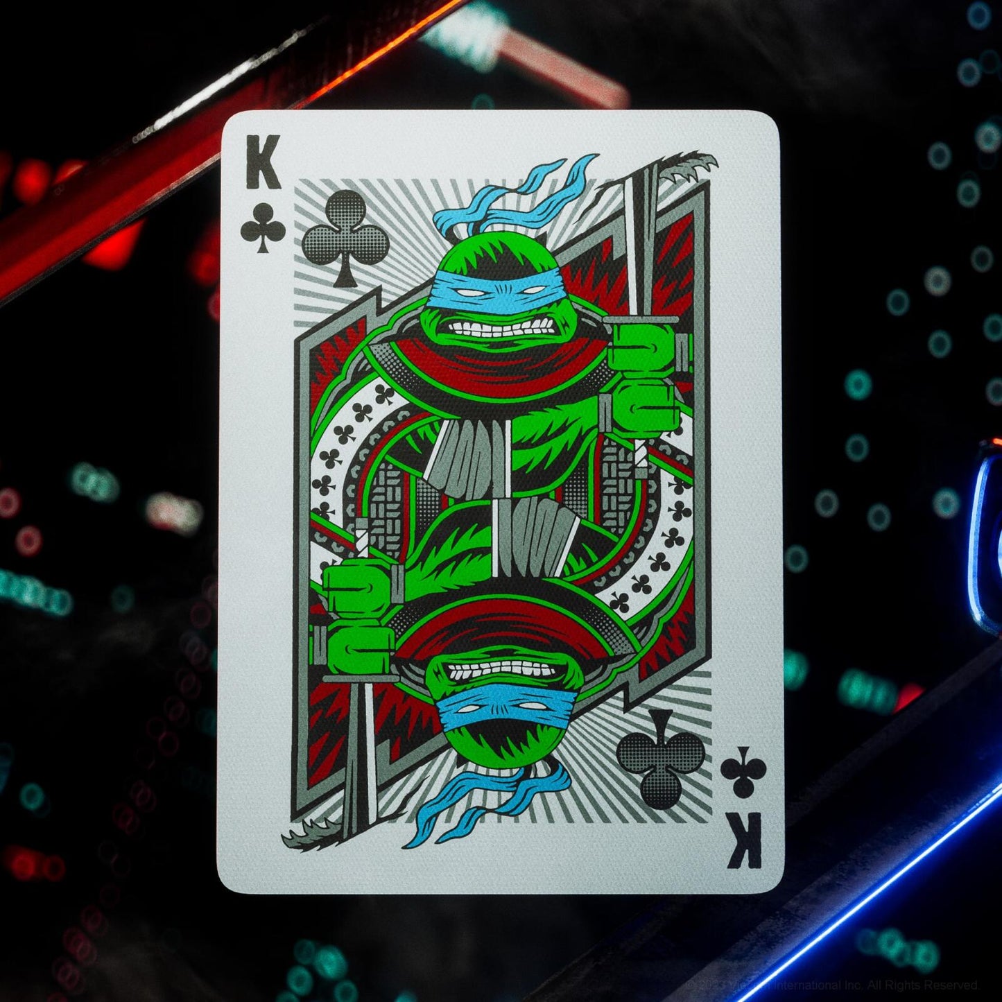 Playing card with a king of clubs design featuring a green character on a dark background with colorful lights.