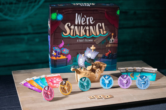 Board game box titled 'We're Sinking!' with game pieces on a wooden surface.