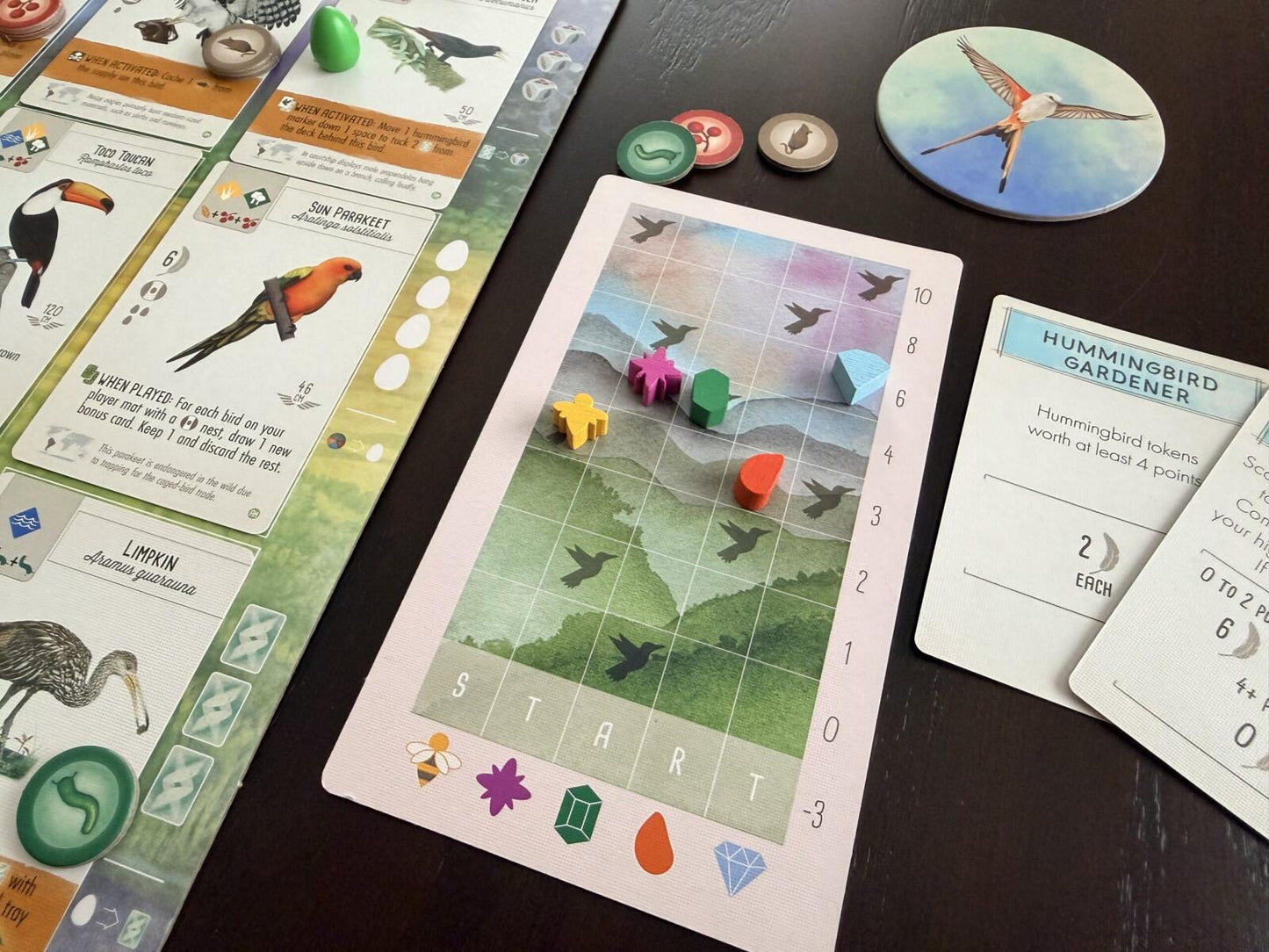 Board game components including cards and a game board on a dark surface